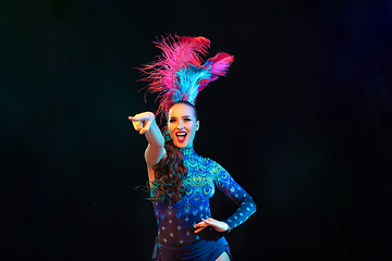 Image showing Beautiful young woman in carnival and masquerade costume in colorful neon lights on black background