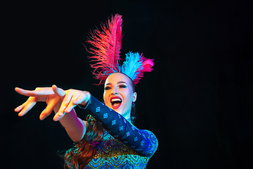 Image showing Beautiful young woman in carnival and masquerade costume in colorful neon lights on black background