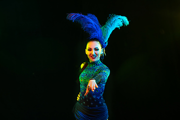 Image showing Beautiful young woman in carnival and masquerade costume in colorful neon lights on black background