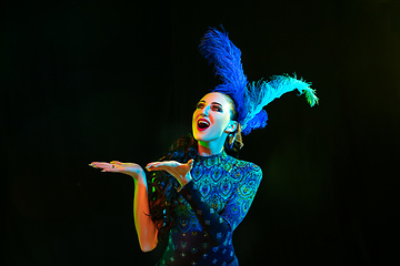 Image showing Beautiful young woman in carnival and masquerade costume in colorful neon lights on black background