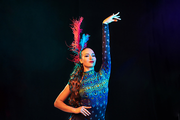 Image showing Beautiful young woman in carnival and masquerade costume in colorful neon lights on black background