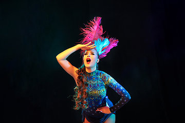 Image showing Beautiful young woman in carnival and masquerade costume in colorful neon lights on black background