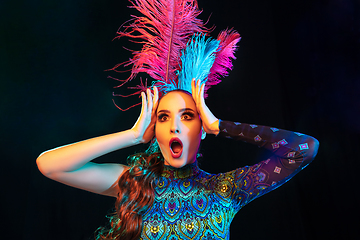 Image showing Beautiful young woman in carnival and masquerade costume in colorful neon lights on black background