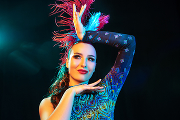 Image showing Beautiful young woman in carnival and masquerade costume in colorful neon lights on black background