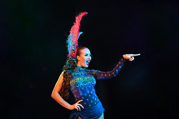 Image showing Beautiful young woman in carnival and masquerade costume in colorful neon lights on black background