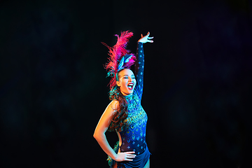 Image showing Beautiful young woman in carnival and masquerade costume in colorful neon lights on black background