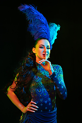 Image showing Beautiful young woman in carnival and masquerade costume in colorful neon lights on black background