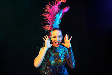 Image showing Beautiful young woman in carnival and masquerade costume in colorful neon lights on black background