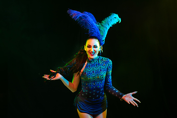 Image showing Beautiful young woman in carnival and masquerade costume in colorful neon lights on black background