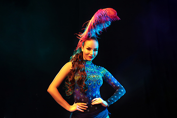 Image showing Beautiful young woman in carnival and masquerade costume in colorful neon lights on black background