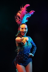 Image showing Beautiful young woman in carnival and masquerade costume in colorful neon lights on black background