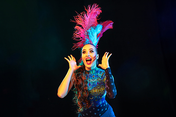 Image showing Beautiful young woman in carnival and masquerade costume in colorful neon lights on black background