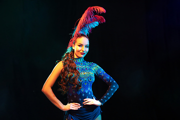 Image showing Beautiful young woman in carnival and masquerade costume in colorful neon lights on black background