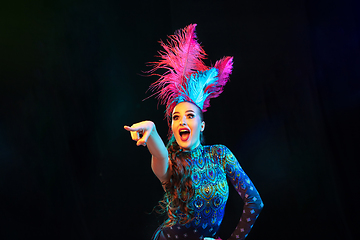 Image showing Beautiful young woman in carnival and masquerade costume in colorful neon lights on black background