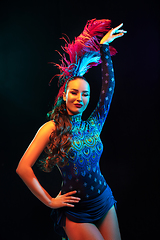 Image showing Beautiful young woman in carnival and masquerade costume in colorful neon lights on black background