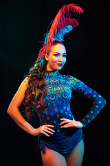 Image showing Beautiful young woman in carnival and masquerade costume in colorful neon lights on black background