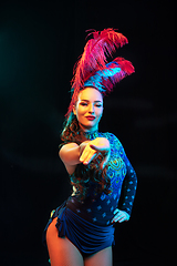 Image showing Beautiful young woman in carnival and masquerade costume in colorful neon lights on black background