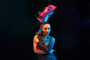 Image showing Beautiful young woman in carnival and masquerade costume in colorful neon lights on black background