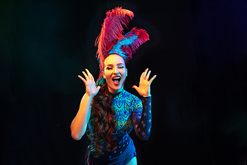 Image showing Beautiful young woman in carnival and masquerade costume in colorful neon lights on black background