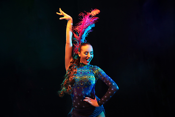 Image showing Beautiful young woman in carnival and masquerade costume in colorful neon lights on black background