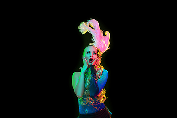 Image showing Beautiful young woman in carnival and masquerade costume in colorful neon lights on black background