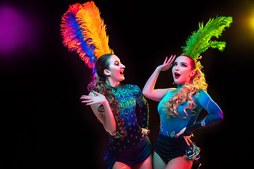 Image showing Beautiful young women in carnival and masquerade costume in colorful neon lights on black background