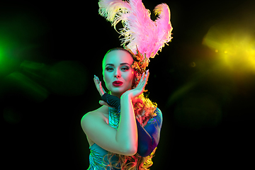 Image showing Beautiful young woman in carnival and masquerade costume in colorful neon lights on black background