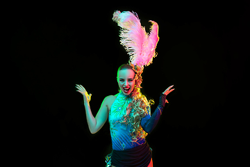 Image showing Beautiful young woman in carnival and masquerade costume in colorful neon lights on black background