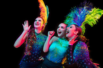 Image showing Beautiful young women in carnival and masquerade costume in colorful neon lights on black background