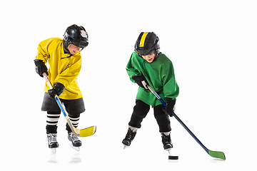 Image showing Little hockey players with the sticks on ice court and white studio background