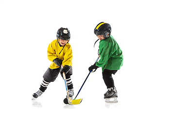 Image showing Little hockey players with the sticks on ice court and white studio background