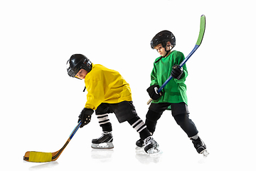 Image showing Little hockey players with the sticks on ice court and white studio background