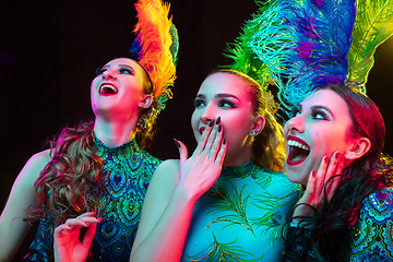 Image showing Beautiful young women in carnival and masquerade costume in colorful neon lights on black background