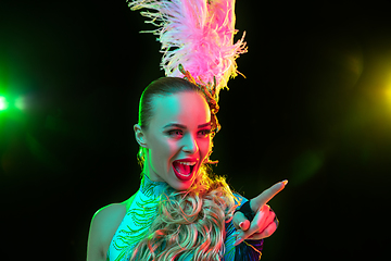 Image showing Beautiful young woman in carnival and masquerade costume in colorful neon lights on black background