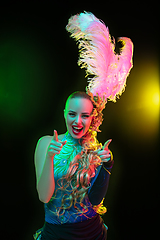 Image showing Beautiful young woman in carnival and masquerade costume in colorful neon lights on black background