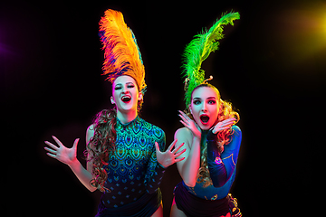 Image showing Beautiful young women in carnival and masquerade costume in colorful neon lights on black background