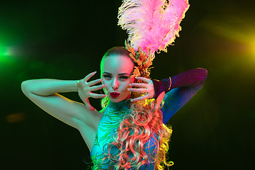 Image showing Beautiful young woman in carnival and masquerade costume in colorful neon lights on black background