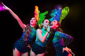 Image showing Beautiful young women in carnival and masquerade costume in colorful neon lights on black background