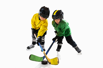 Image showing Little hockey players with the sticks on ice court and white studio background