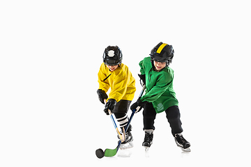 Image showing Little hockey players with the sticks on ice court and white studio background