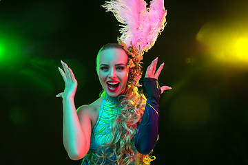 Image showing Beautiful young woman in carnival and masquerade costume in colorful neon lights on black background