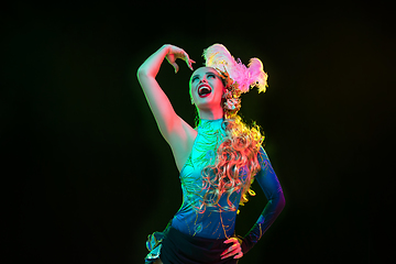 Image showing Beautiful young woman in carnival and masquerade costume in colorful neon lights on black background