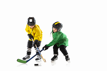 Image showing Little hockey players with the sticks on ice court and white studio background