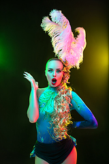 Image showing Beautiful young woman in carnival and masquerade costume in colorful neon lights on black background