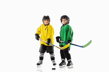 Image showing Little hockey players with the sticks on ice court and white studio background