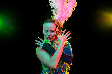 Image showing Beautiful young woman in carnival and masquerade costume in colorful neon lights on black background