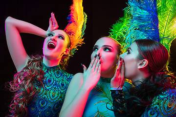 Image showing Beautiful young women in carnival and masquerade costume in colorful neon lights on black background