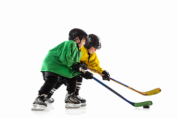 Image showing Little hockey players with the sticks on ice court and white studio background