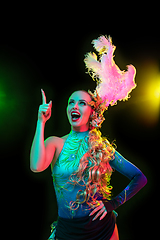 Image showing Beautiful young woman in carnival and masquerade costume in colorful neon lights on black background