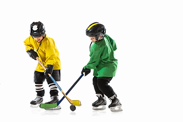 Image showing Little hockey players with the sticks on ice court and white studio background